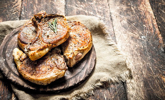 Grilled pork steak with spices. On wooden background.