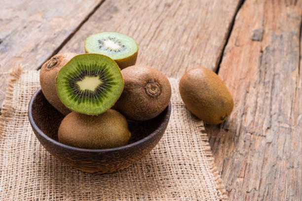 istock Kiwi fruit in a bowl on wooden background. 954553086