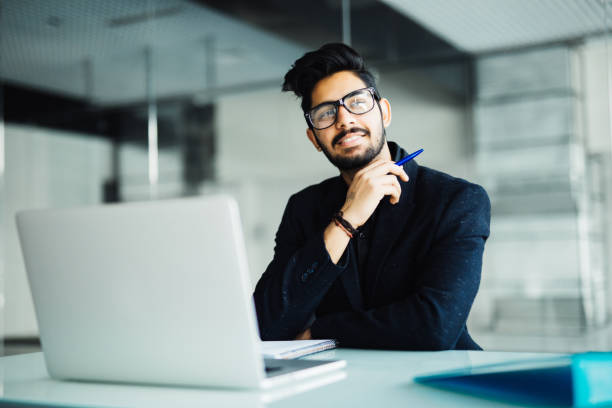 istock Indian businessman with laptop computer and papers working at office 954554718