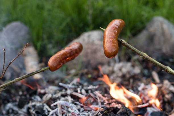 leckere wurst am lagerfeuer zubereitet. ein festtagsessen, das im freien zubereitet wird. jahreszeit des frühlings. - saussage stock-fotos und bilder