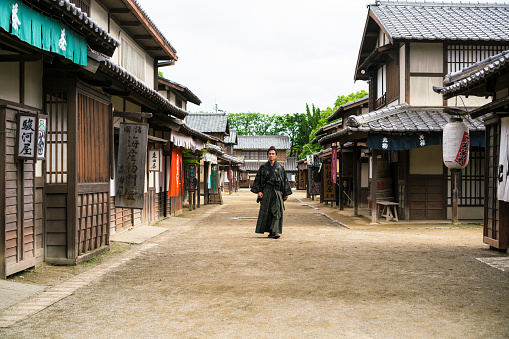 Japanese warrior Samurai with Sword walking on an old empty street in Japan.