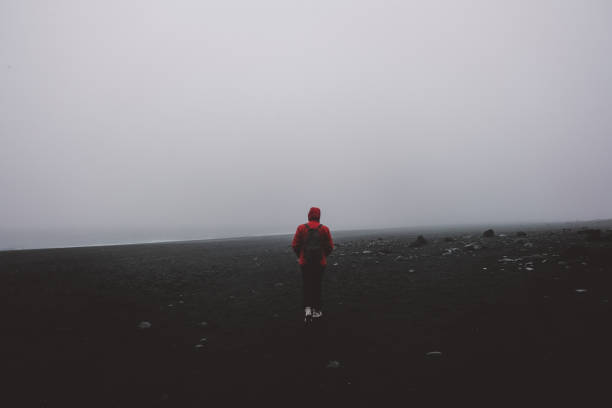istock Man in red on black sand beach in Iceland 954559986