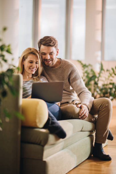 istock Young happy couple using computer in the living room. 954560148