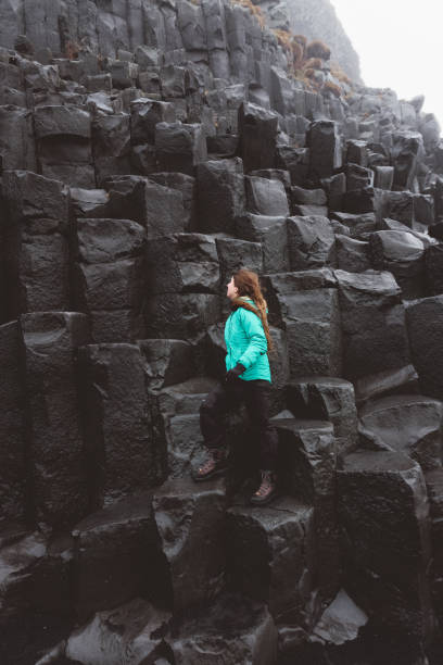 istock Woman staying on basalt columns in black sand beach in Iceland 954560698