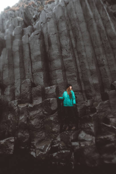 istock Woman staying on basalt columns in black sand beach in Iceland 954560704