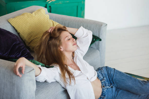 istock Young woman relaxing at cozy sofa in light room 954565482
