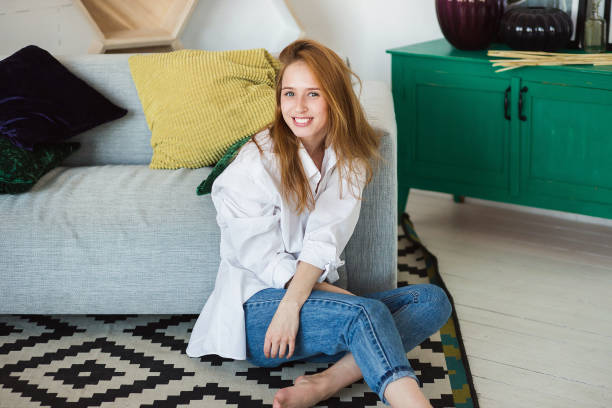 istock Young woman relaxing at cozy sofa in light room 954565510