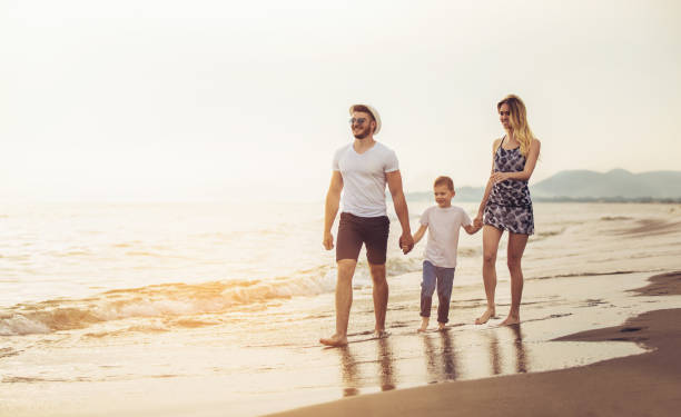 istock Mother and father with their son walking together on a quiet beach. 954569212