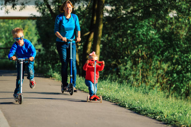 istock mother with kids riding scooters in nature 954569940