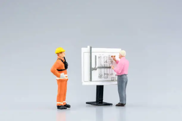 Photo of Miniature engineering people and architecture working on construction drawing