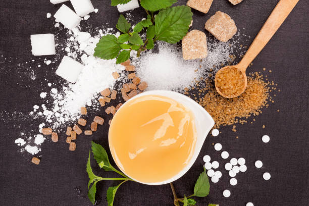 Various types of sugar - brown, white, crystal, cane, powdered and artificial sweeteners with honey in bowl from above.