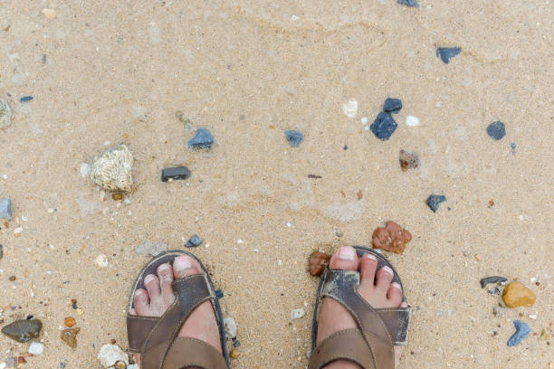 istock man standing on the beach. white sand and clear water. first-person view 954574744