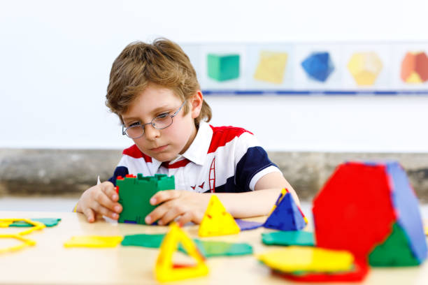 istock Happy kid boy with glasses having fun with building and creating geometric figures, learning mathematics and geometry 954576154