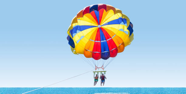 mutlu yaz aylarında parasailing tropik sahilde çift. i̇ki orta hava asılı paraşüt altında. eğleniyor. tropik cenneti. olumlu insan duyguları, duygular, aile, seyahat, tatil. - parasailing stok fotoğraflar ve resimler