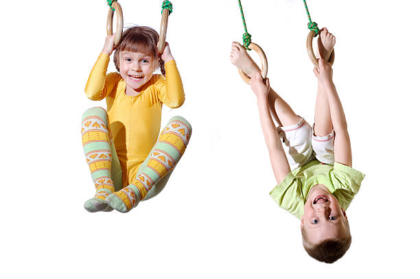 Little boy hanging on gymnastic rings on outdoor playground. Summer active sport leisure for kids.