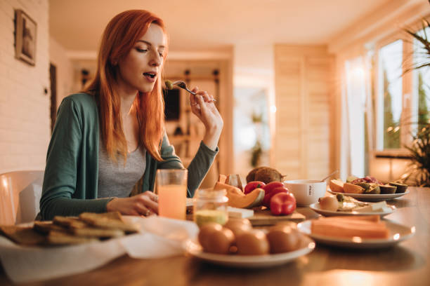 istock Young redhead woman having breakfast in dining room. 954624888