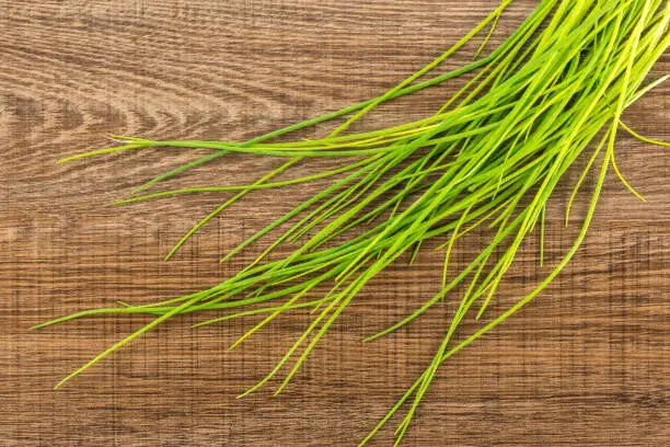 Photo of Fresh Raw Chives on brown wood