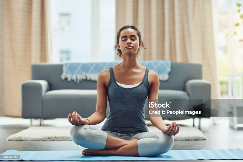 Meditation is how I stay focused in life Shot of an attractive young woman practicing yoga at home Meditating Stock Photo