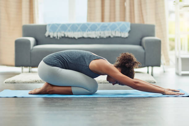 Breathing is important in yoga Shot of an attractive young woman practicing yoga at home childs pose stock pictures, royalty-free photos & images