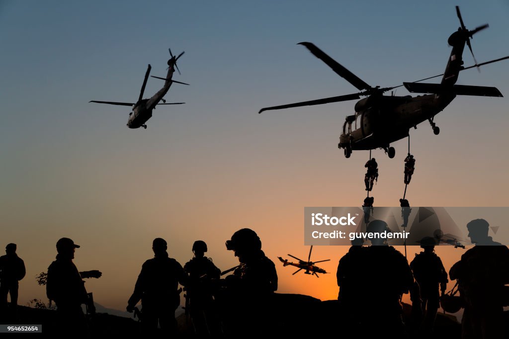 Siluetas de soldados en misión militar al atardecer - Foto de stock de Guerra libre de derechos