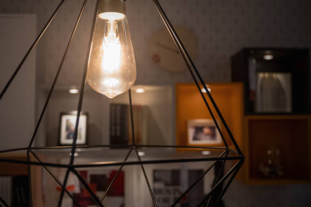 istock A glowing light bulb in modern lamp with blurred decoration shelf background 954656484