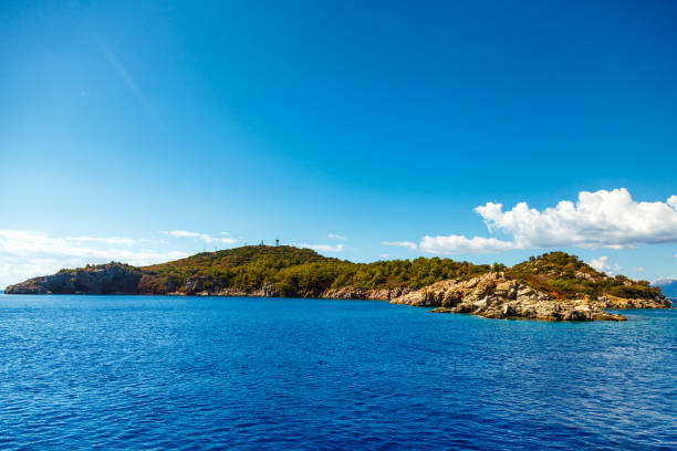 istock Rocky coast with trees in the Aegean Sea. Beautiful white clouds 954657472