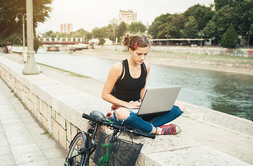 Young hipster girl with laptop outside.