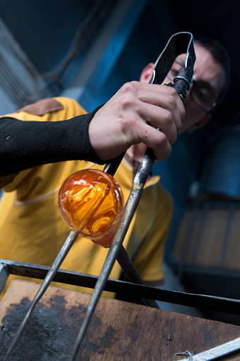 Young artist blowing glass.