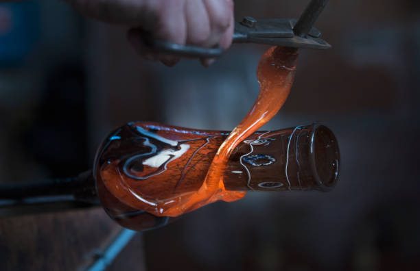 Glassblowing worker cutting liquid glass Glassblowing worker cutting liquid glass murano stock pictures, royalty-free photos & images