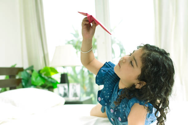 istock Girl throwing paper airplane at home 954669334