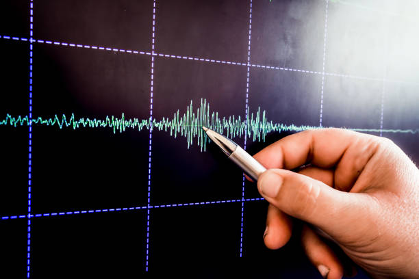 earthquake graph hand with pencil points web earthquake graph on monitor seismograph stock pictures, royalty-free photos & images
