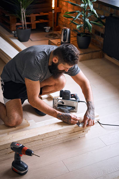 istock Carpenter measuring boards in a room with loft interior. 954676936