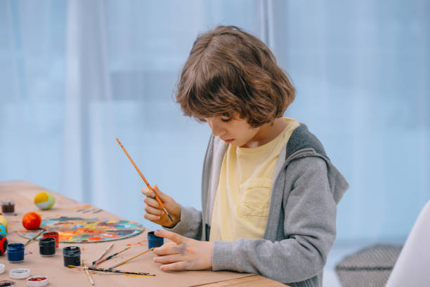 istock focused little kid painting easter eggs 954681868