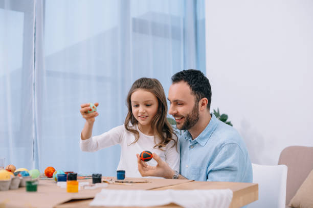 istock happy young father painting easter eggs with daughter 954688504
