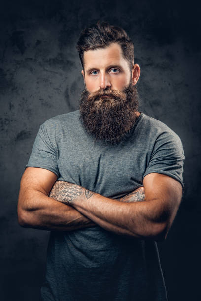 istock Bearded male with tattoos on arms over grey background. 954689678