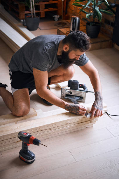 istock Carpenter measuring boards in a room with loft interior. 954693014