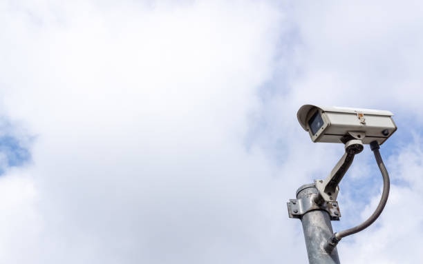 istock Security CCTV surveillance camera against a sky with big white clouds, big empty copy space for your text 954694584
