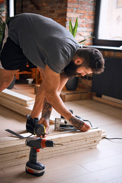 istock Carpenter measuring boards in a room with loft interior. 954696250