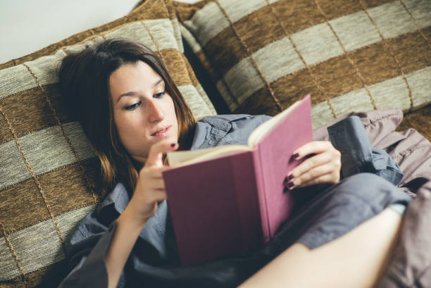 istock Woman relaxing in bed with her favorite book. 954697644