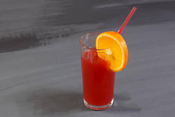 istock Fresh juice, straw and mandarin slice on a gray 954705538