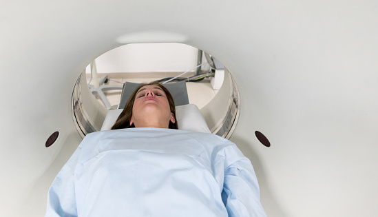 Female patient lying down with her eyes closed ready for an MRI exam