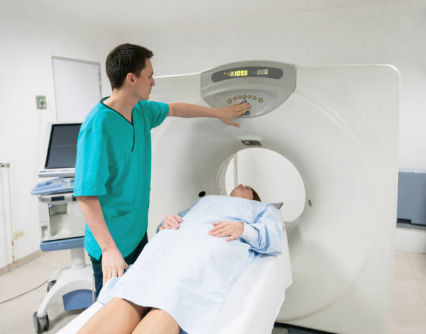 istock Male radiologist getting the machine ready for a CT scan and patient already lying down 954708148