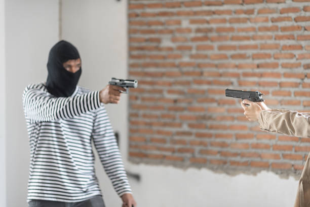 istock A robber dressed in black pointing a gun at woman 954711324