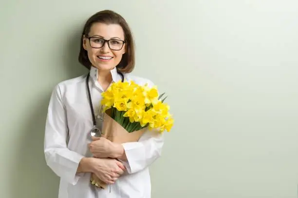 Smiling woman doctor with bouquet of flowers. World health day, doctors day