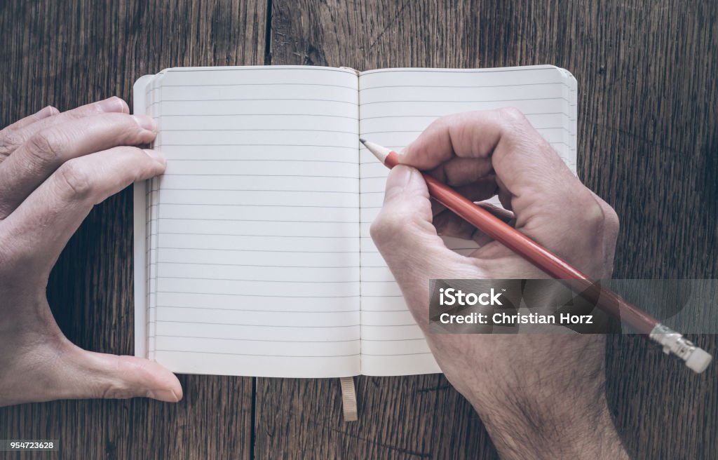 Draufsicht der Mann mit Bleistift schreiben auf Notizblock auf Schreibtisch aus Holz - Lizenzfrei Handschrift Stock-Foto