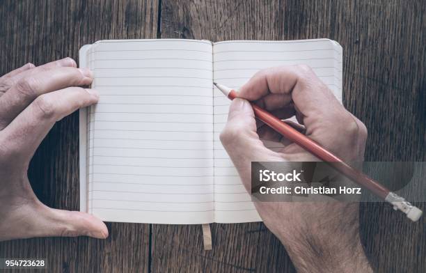 Draufsicht Der Mann Mit Bleistift Schreiben Auf Notizblock Auf Schreibtisch Aus Holz Stockfoto und mehr Bilder von Handschrift