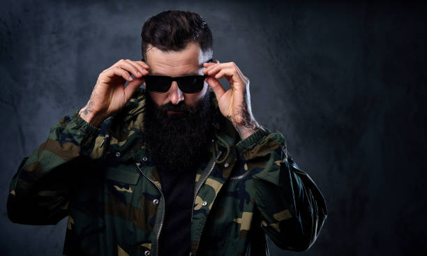 istock A man dressed in a camouflage jacket over grey background. 954726256