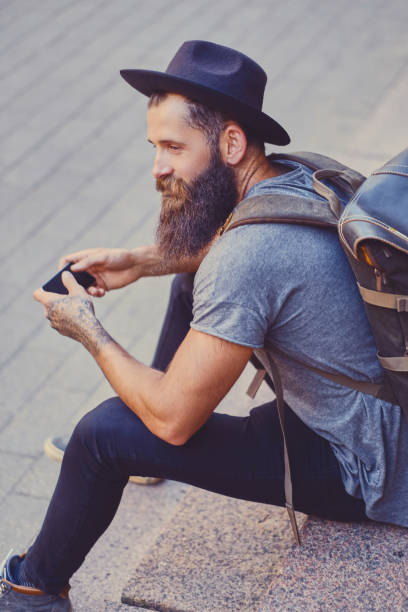 istock Bearded traveller male using a smartphone in a town. 954750288