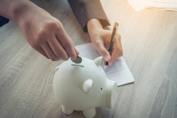 Close up of hands business women putting coins into piggy bank. Investment and saving strategy concept. Close up of hands business women putting coins into piggy bank. Investment and saving strategy concept. financial wellbeing stock pictures, royalty-free photos & images