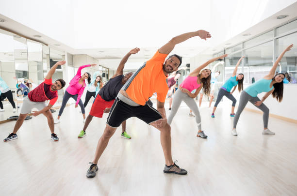 istock Cheerful instructor guiding his class to strecth at the gym 954755040